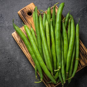 May include: A bunch of fresh green string beans on a wooden cutting board. The beans are arranged in a fan shape, with the tips of the beans pointing towards the top of the image.