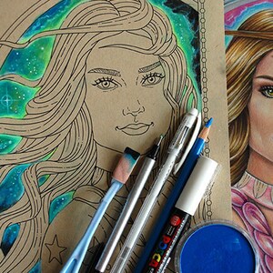 Może przedstawiać: Zbliżenie na rysunek kobiety z długimi, falującymi włosami, tłem galaktyki i różnymi przyborami artystycznymi, w tym niebieskimi, białymi i czarnymi markerami, niebieskim ołówkiem i małym pojemnikiem niebieskiej farby.