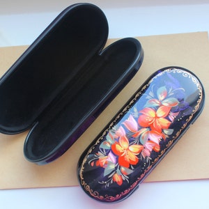 May include: A black and blue glasses case with a floral design. The case is decorated with orange, pink, and green flowers. The case is closed and the floral design is visible on the top.