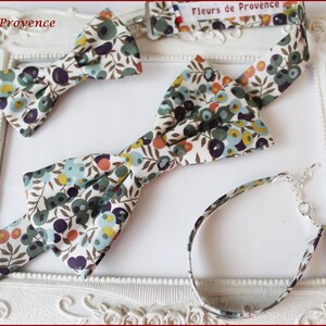 Puede incluir: Tres pajaritas a juego y una pulsera con un estampado floral. La tela es blanca con flores verdes, azules, amarillas y naranjas. Las pajaritas son de diferentes tama&ntilde;os. La pulsera est&aacute; hecha de tela y tiene un cierre plateado.