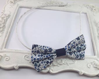 May include: A white headband with a blue and white floral bow. The bow has a navy blue ribbon in the center.