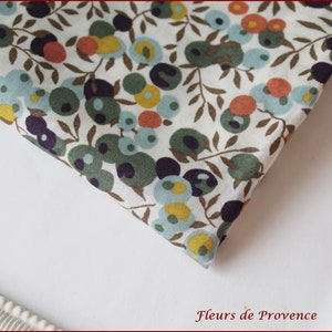 Puede incluir: Tela blanca con un patr&oacute;n repetido de c&iacute;rculos verdes, azules, amarillos y naranjas sobre ramas marrones. La tela est&aacute; doblada por la mitad y el patr&oacute;n es visible en ambos lados.