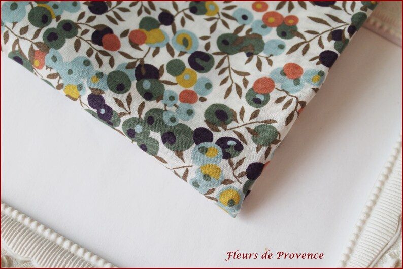 Puede incluir: Tela blanca con un patr&oacute;n repetido de c&iacute;rculos verdes, azules, amarillos y naranjas sobre ramas marrones. La tela est&aacute; doblada por la mitad y el patr&oacute;n es visible en ambos lados.