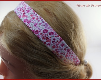 May include: A pink and white floral headband with a white background and pink flowers. The headband is made of fabric and is worn on a person's head.