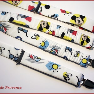 Peut inclure: Quatre bretelles blanches sur le thème de Mickey Mouse. Les bretelles ont un fond blanc avec des images de dessins animés colorés de Mickey Mouse, des lunettes de soleil et les mots "Fun in the sun" et "Stay cool".