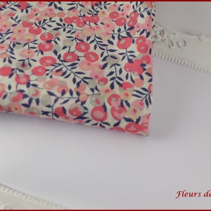 May include: A white fabric with a pink and blue floral pattern. The fabric is folded and placed on top of a white picture frame. The frame has a decorative border and the text "Fleurs de Provence" is printed on the bottom right corner.