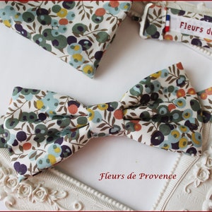 Puede incluir: Una pajarita blanca con un patr&oacute;n floral en tonos verdes, azules, naranjas y amarillos. La pajarita est&aacute; hecha de tela y tiene una etiqueta que dice "Fleurs de Provence".