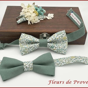 Peut inclure: Deux nœuds papillon, un à motifs floraux et un vert uni, avec une boutonnière assortie et une boîte en bois. Les nœuds papillon sont présentés sur une surface blanche avec le texte "Fleurs de Provence".