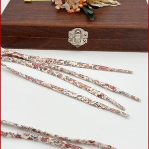 Pair of Liberty fabric laces with clay pink flowers on an ecru and sage background