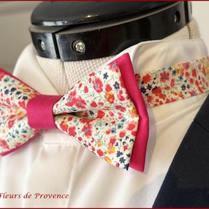 May include: A pink and white bow tie with a floral pattern. The bow tie is made of fabric and has a pink trim.
