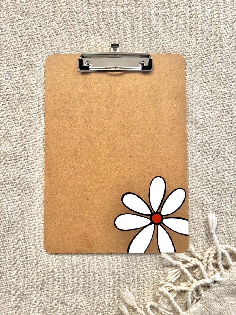 May include: A brown clipboard with a white daisy with a red center painted on the bottom right corner.