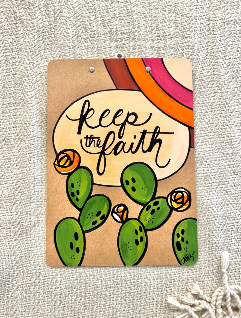 May include: A brown clipboard with a painted design featuring a cactus, flowers, and the text "keep the faith".