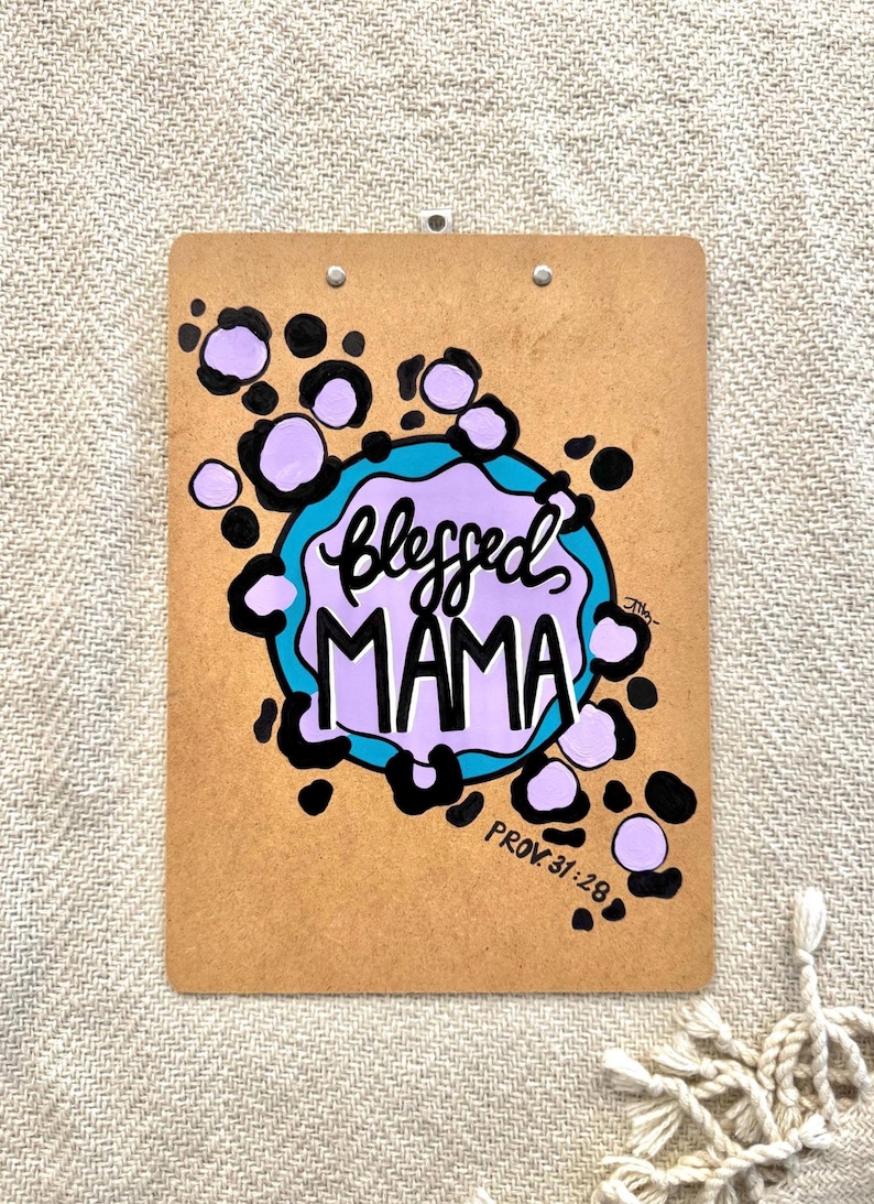 May include: A brown clipboard with a purple and blue design. The design features a circle with the words "Blessed Mama" and the text "Prov. 31:28".