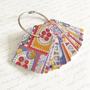May include: A set of patterned index cards attached to a silver ring. The cards display illustrations of tomatoes, lemons, and fish, with the text "BELLA VITA" on one. The cards have a scalloped edge and are in various colours.