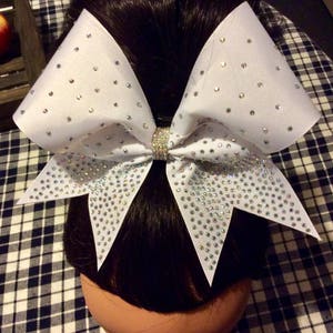 May include: A large white cheer bow with a white ribbon and rhinestones.