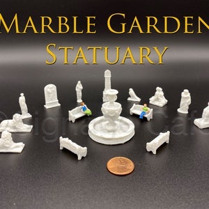 May include: A set of miniature white marble garden statuary, including a fountain, benches, a lion, and figures. The set is arranged on a black surface with a penny for scale.