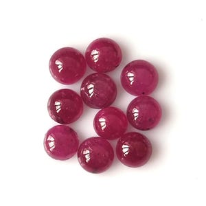 May include: Ten round, red ruby cabochons, each with a smooth, polished surface.