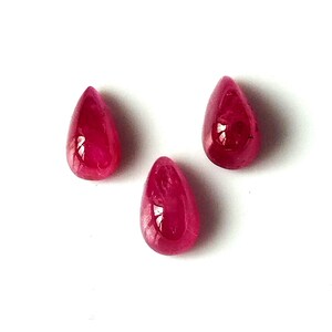 Peut inclure: Trois pierres précieuses rouges en forme de poire, chacune avec une surface lisse et polie.