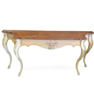 May include: A console table featuring a rectangular wooden top with a brown finish and a curved, off-white base. The frame is decorated with gold-toned accents and a central carved floral motif, supported by four slender, curved cabriole legs.