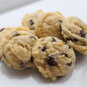 May include: Close-up of a plate of five soft, light brown, almond flour chocolate chip cookies.