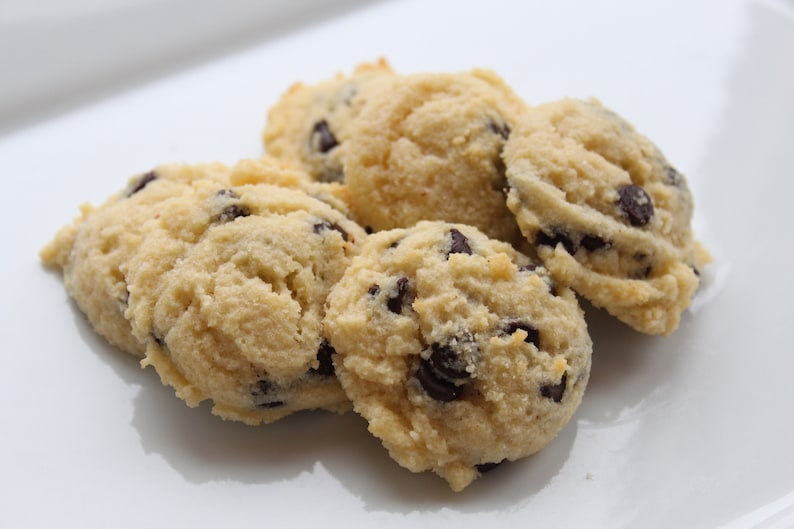 May include: Close-up of a plate of five soft, light brown, almond flour chocolate chip cookies.