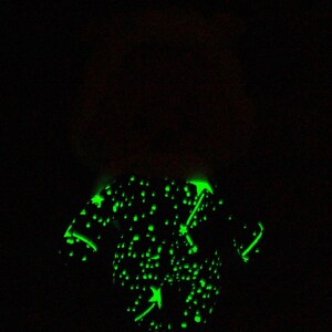 May include: A black and green glow-in-the-dark t-shirt with a constellation design and a green arrow pointing to the right.