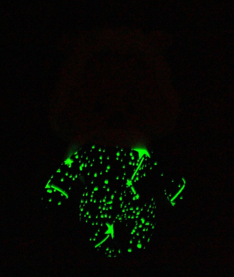 May include: A black and green glow-in-the-dark t-shirt with a constellation design and a green arrow pointing to the right.