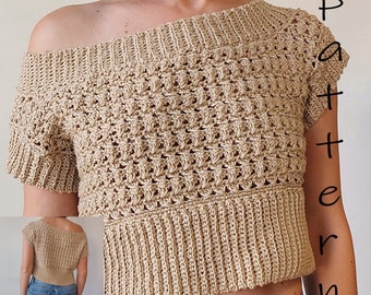 May include: A beige crochet top with a wide, off-the-shoulder neckline and short sleeves. The top has a textured stitch pattern and a ribbed hem.