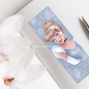 Op de afbeelding: Een blauwe en witte bladwijzer met een portret van Assepoester, een Disney-prinses, in een lichtblauwe jurk en een wit hoofdband. De achtergrond is lichtblauw met een wit bloemenpatroon.