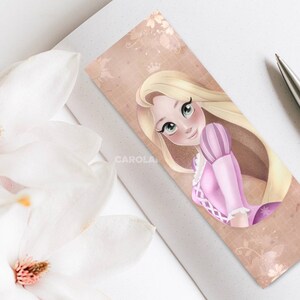 Op de afbeelding: Een bladwijzer met een cartoonillustratie van Rapunzel uit de Disney-film Tangled. Ze heeft lang blond haar, een roze jurk en een kroon. De achtergrond is lichtbruin met een bloemmotief.