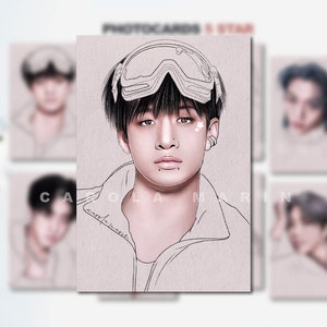 Op de afbeelding: Een fotokaart met een tekening van een persoon met zwart haar die een skibril draagt. De tekening is in zwart-wit op een lichtroze achtergrond. De fotokaart heeft de tekst "PHOTOCARDS 5 STAR" bovenaan.