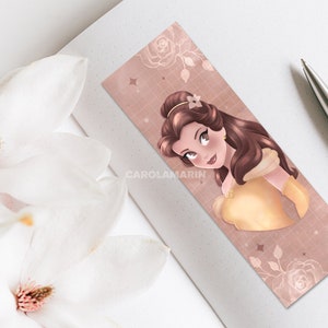 Op de afbeelding: Een roze en gouden bladwijzer met een cartoonillustratie van Belle uit Disney's Belle en het Beest. De bladwijzer heeft een subtiel rasterpatroon en een bloemmotief.