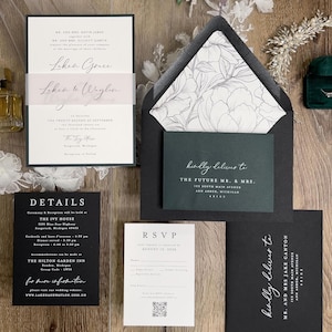 May include: Black and white wedding invitation suite with green and white floral envelope liner. The invitation features the couple's names, wedding date, and location. The RSVP card includes a QR code. The details card includes information about the ceremony and reception. The outer envelope is black with white calligraphy.
