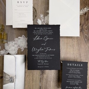 May include: Black and white wedding invitation suite with a black background and white text. The invitation features the names "Loken Grace" and "Waylon James" and the date "September 22, 2026". The RSVP card has a white background and black text. The details card has a black background and white text.