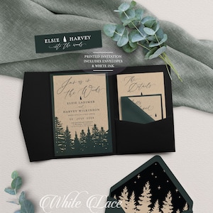 May include: A folded wedding invitation with a forest theme. The invitation is printed on kraft paper with a dark green envelope. The text on the invitation reads "Join us in the Woods" with the names Elsie Ladimer and Harvey Wilkinson and the date July 22, 2024. The envelope has a black liner with a gold silhouette of trees.