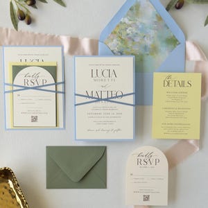 Pale blue, butter yellow and ivory Lucia wedding invitation suite featuring a layered invitation, yellow details card, ivory arch RSVP card and blue envelope with a romantic watercolor floral liner.