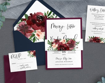 Puede incluir: Un conjunto de invitaciones de boda con flores de color burdeos y rosa pálido, presentado en un sobre azul marino. La invitación incluye los nombres "Mergen Litaro" y "Yander Russel", con la fecha "Viernes, 05, 2023" y la ubicación "Mizo Ridge Farm, Appleton, Wisconsin".