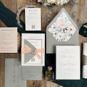 May include: Wedding invitation suite with a gray and peach color scheme. The invitation features a floral design with the text "Lokea Grace and Waylon James" and the date "The Twenty Second of September". The RSVP card has a peach ribbon and a wax seal.