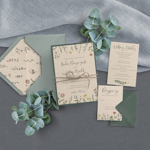 May include: A wedding invitation suite with a floral design. The invitation features a rustic brown paper background with a green border and a floral pattern. The text on the invitation reads "Together with their families, Amelia Plenger Smith and  Letter Asarold, Saturday, 1 May 2022 at the Cedar Creek, 12:00 PM,  Sudcow Valley Winery, Pittsburgh, Pennsylvania, Reception to follow".