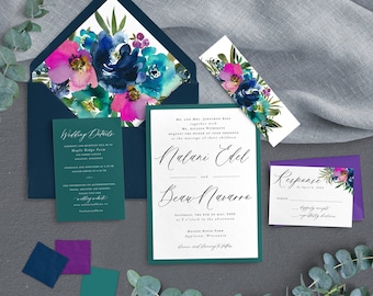 May include: Wedding invitation suite with a teal, navy, and purple color scheme. The invitation features a watercolor floral design with pink, blue, and green flowers. The text on the invitation reads "Malani Edel and Beau Navarro".