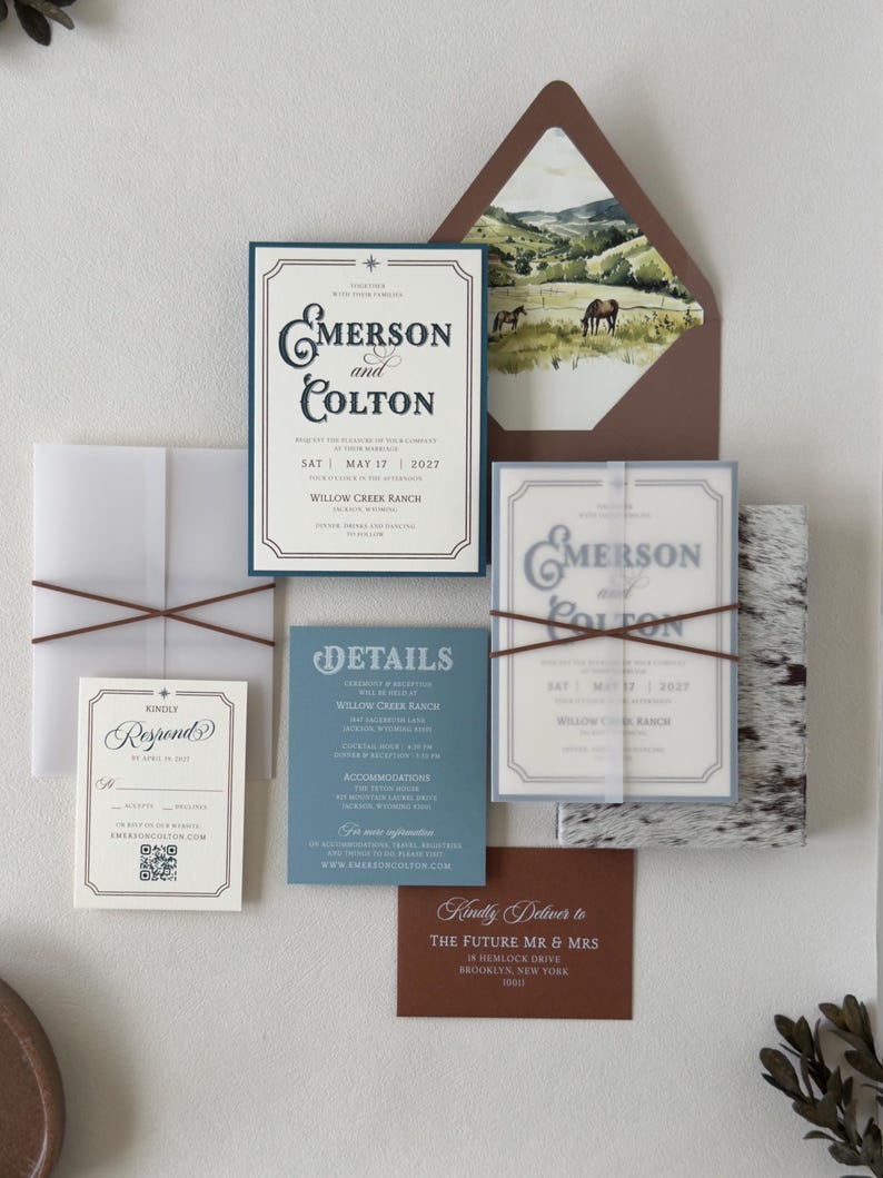 Full Emerson western wedding invitation suite featuring dusty blue, ivory and warm brown stationery with a scenic ranch envelope liner and layered translucent details.