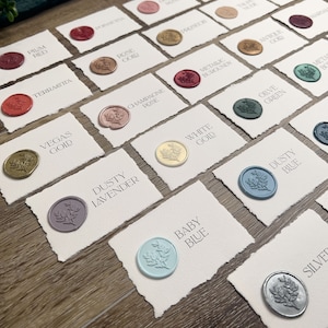 May include: A collection of rectangular white cards with deckled edges, each featuring a circular wax seal with a floral design. The cards are labeled with color names including Plum Red, Poinsettia, Rose Gold, Champagne Rose, Vegas Gold, Dusty Lavender, White Gold, Dusty Blue, Baby Blue, and Silver.