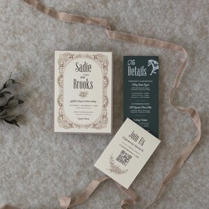 Vintage-inspired ivory wedding invitation with decorative border paired with dark green details card and QR code RSVP card, styled with soft taupe ribbon.