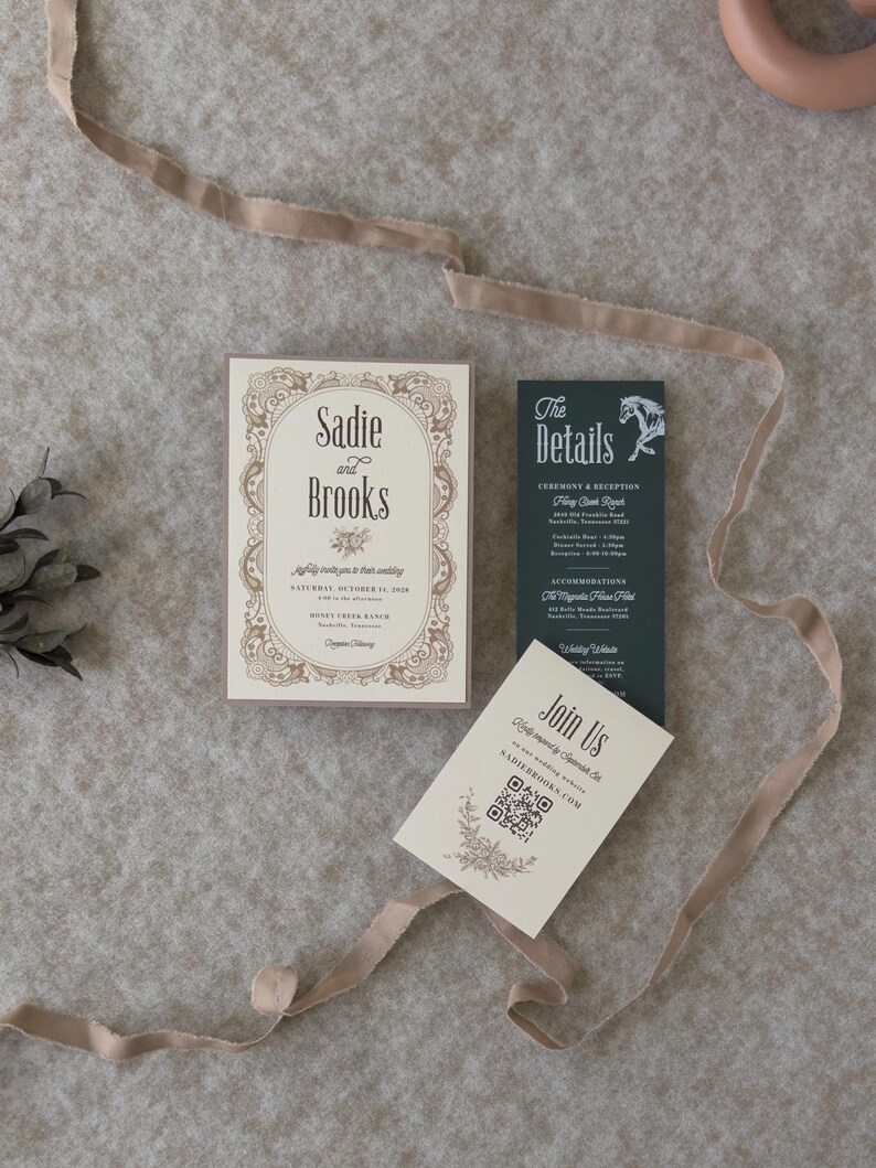 Vintage-inspired ivory wedding invitation with decorative border paired with dark green details card and QR code RSVP card, styled with soft taupe ribbon.