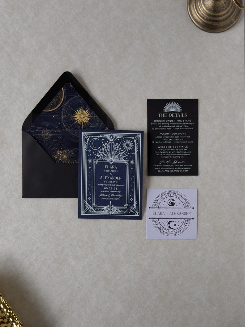 Elara navy blue wedding invitation with ornate silver Art Deco celestial border, displayed alongside a black envelope with gold astronomical liner, black details card, ivory arch RSVP, and lavender celestial tag.