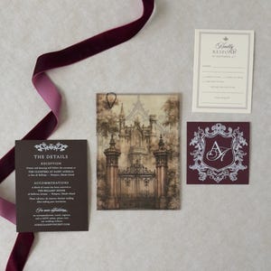 Aurelia wedding invitation accessories featuring dramatic sepia castle-gate vellum, dark Bitter Chocolate details card, ivory traditional RSVP, and ornate Claret crest tag arranged with burgundy velvet ribbon.