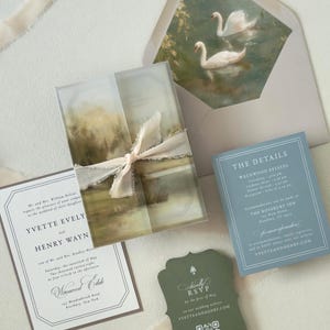 Elegant country wedding invitation suite featuring an ivory invitation, dusty blue details card, scalloped green RSVP card, scenic landscape vellum wrap and romantic swan envelope liner.