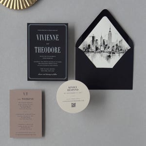 Black Vivienne wedding invitation suite with taupe details card, ivory round RSVP card and coordinating skyline-lined envelope styled on a neutral background.
