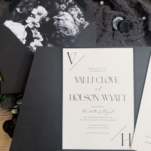 Puede incluir: Invitaci&oacute;n de boda en blanco y negro con un dise&ntilde;o floral en el sobre. El texto de la invitaci&oacute;n dice: "Por favor, &uacute;nase a nosotros para la boda de Valli Clove y Holson Wyatt el s&aacute;bado 25 de agosto de 2025 a las 4:00 p. m. en Everlynns Place, Nueva York, Nueva York. Recepci&oacute;n a continuaci&oacute;n."