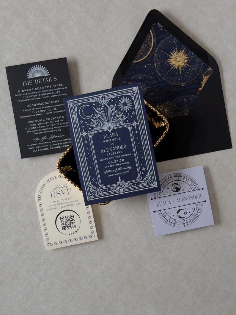 Elara celestial wedding invitation suite featuring a navy blue invitation with intricate silver Art Deco sun, moon, and star illustrations, black details card, ivory arch RSVP card, lavender celestial tag, and black A7 envelope with gold astronomical chart liner.